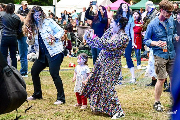 Two women and a little girl dancing at a festival