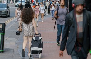 Various people walking along a pavement in a high street