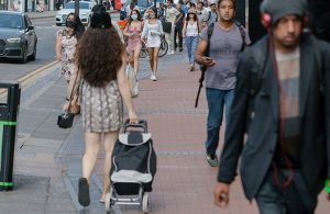 Various people walking along a pavement in a high street