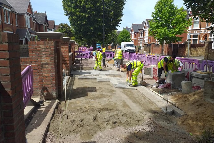 4 x workmen laying new paving wearing high vis outfits