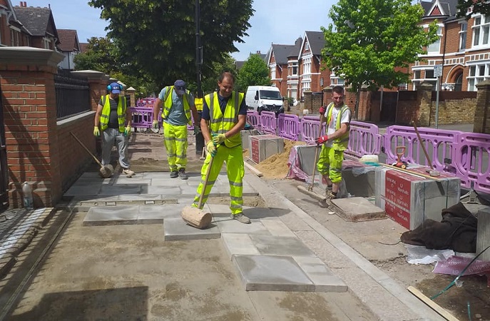 4 x workmen in high vis outfits replacing paving slabs