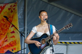 Woman holding a guitar and singing into a microphone