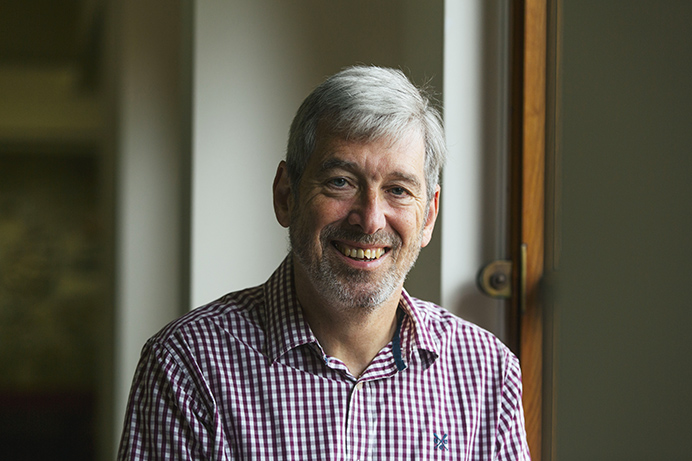 Smiling man, sitting down and looking towards camera