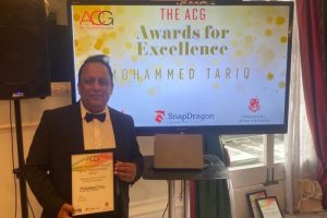 Senior trading standards officer, Mohammed Tariq holding his award in front of a TV screen