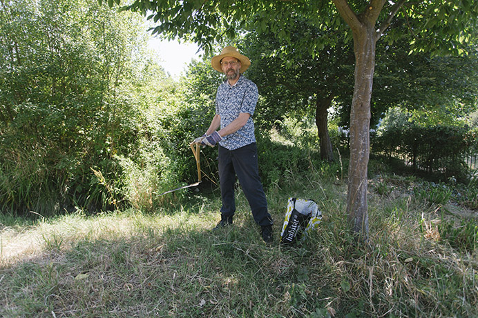 Man standing under a tree holding a scythe