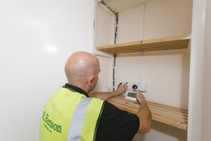 Man looking at electrical equipment in a cupboard