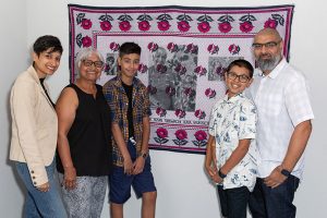Two adults and two children standing in front of a tapestry