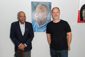 Two men standing in front of a painting