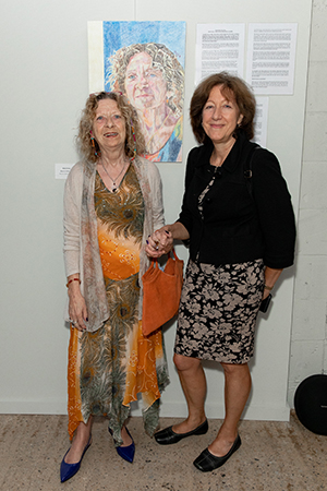 Two women standing in front of a painting