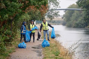 Group of people on a canal towpath with rubbish bags, picking up litter
