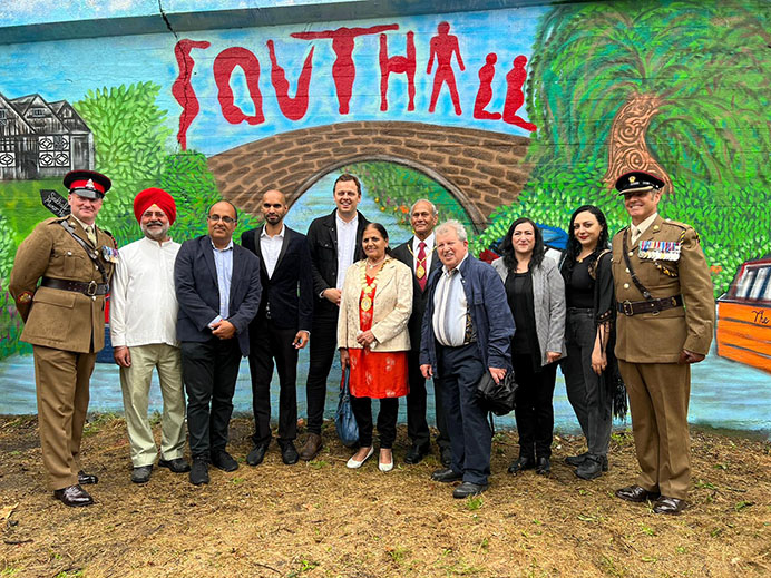 Group of people standing in front of a wall with a painted mural on it