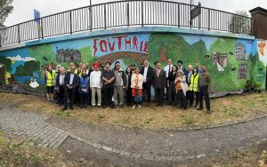 Large group of people standing in a line in front of wall with painted mural