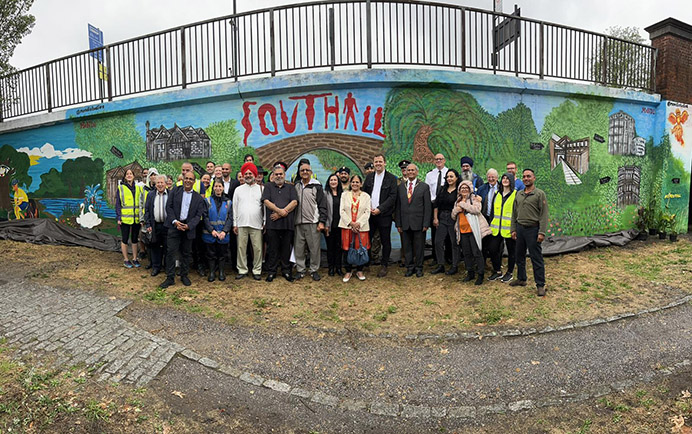 Large group of people standing in a line in front of wall with painted mural