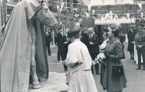 Queen and other dignitaries next to a statue of a horse