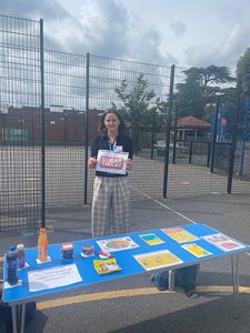 Woman standing behind table with a display of information and posters