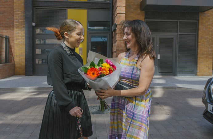 Ana-Maria, a resident at the Copley estate in Hanwell, receiving a bunch of flowers from Cllr Lauren Wall