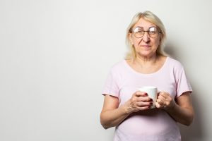 Portrait of a woman in t-shirt and glasses holding a mug in her hands