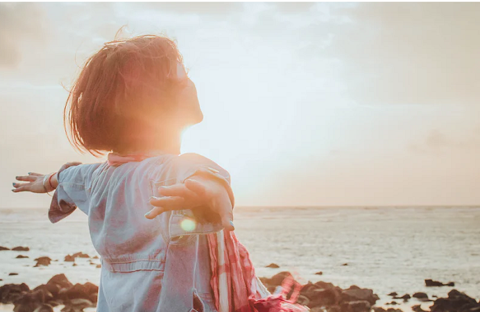 woman looking out at the sea and the sunshine