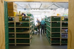 A food warehouse - rows of shelving with green plastic baskets containing items