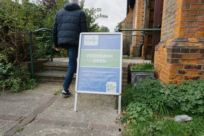 A man walks past a welcome sign outside the Hanwell centre of Ealing Foodbank