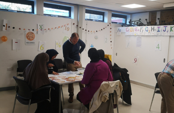 A group of adults gathered around a table playing a maths related game indoors