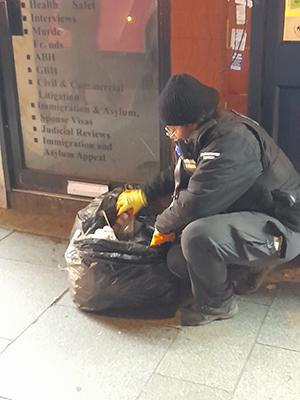 Officer checking through a black sack of rubbish