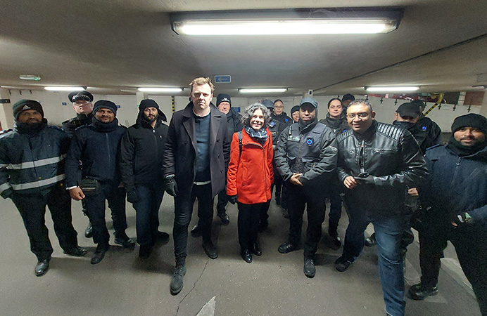 Two councillors surrounded by a group of enforcement officers in uniform