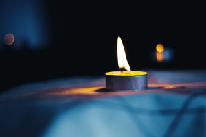 Candle burning on table draped in material with Star of David motif