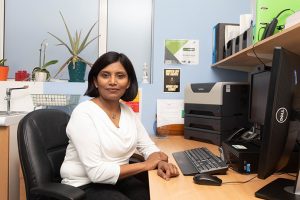 Woman GP sitting at a desk and looking at the camera