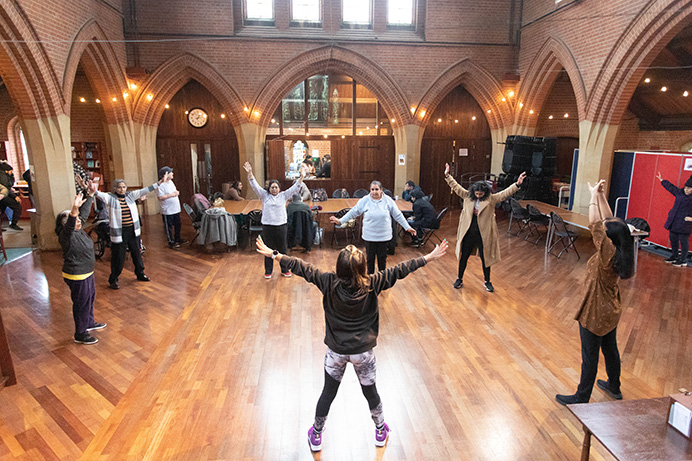 A zumba class in a church with an instructor and around a dozen participants