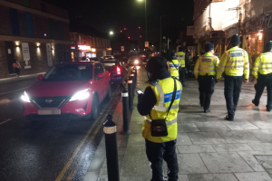 Council officer in high visibility vest issuing a parking fine at night.