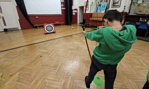 A boy with bow and arrow at an archery workshop, as part of the HAF programme