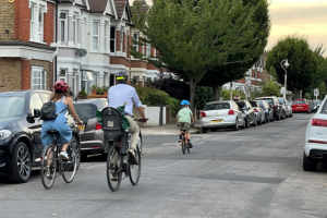 A woman, a man and a child all cycling on a London street