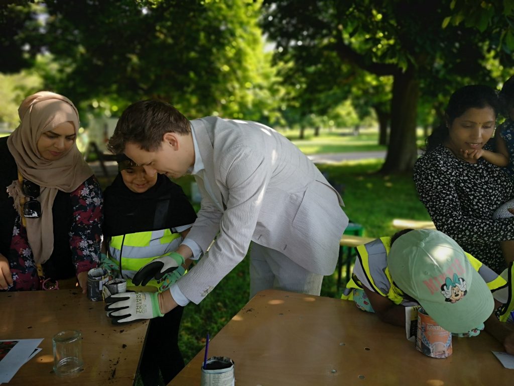 Cllr Peter Mason with school children and parents in the park planting