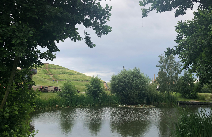 A green open space with trees and water with Northala Fields in the background