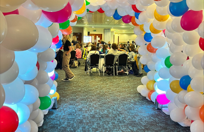 A group of people sitting with colourful balloons