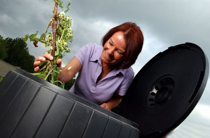 woman putting branches into compost bin