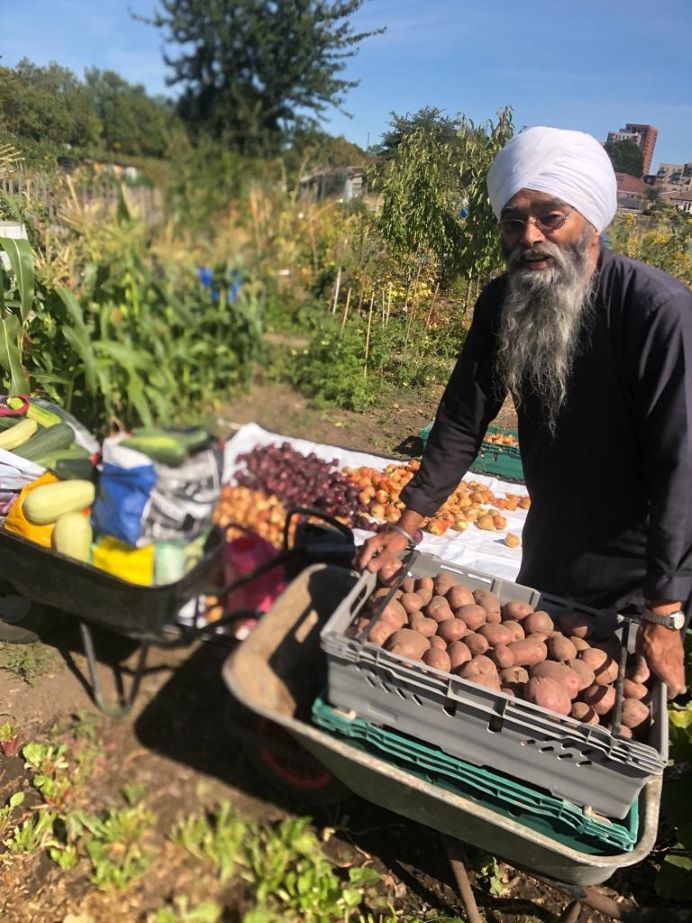 man in allotment surrounded by produce
