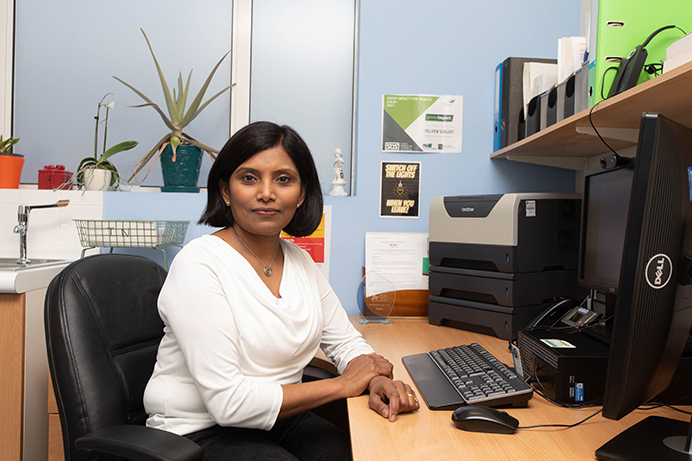 Female GP in her office sitting at her desk
