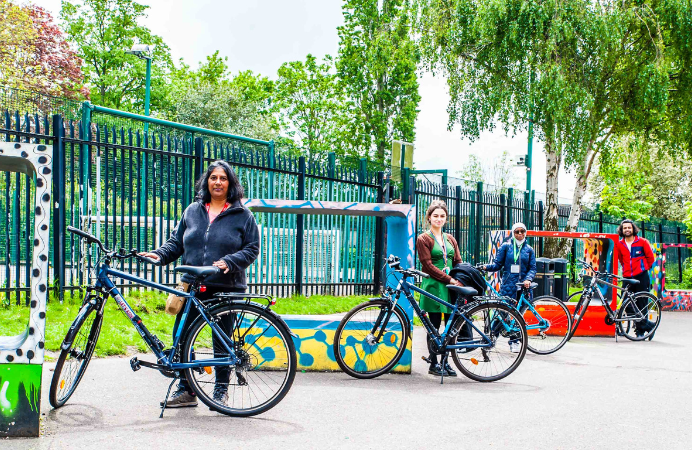 Three women standing next to their bikes outdoors