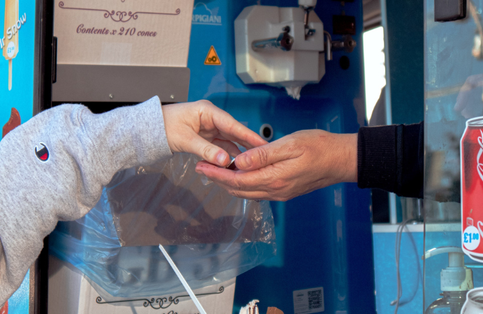 A child's hand passing on coins in a man's hand in an ice cream van