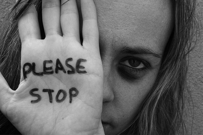 Woman holding up her hand to her face. Message written on hand saying please stop