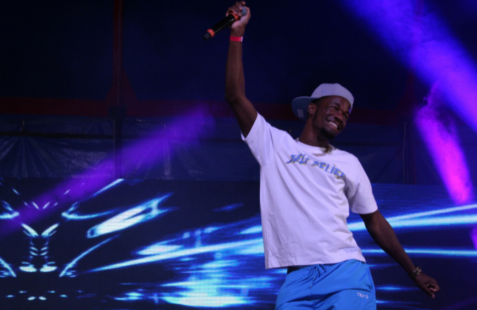 A black man with a microphone on a stage also smiling