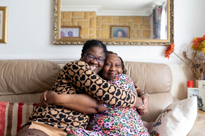 female carer and her foster placement daughter having a hug on the sofa at home