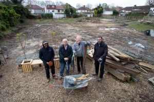 four volunteers with hand tools in the open space that has been cleared of waste