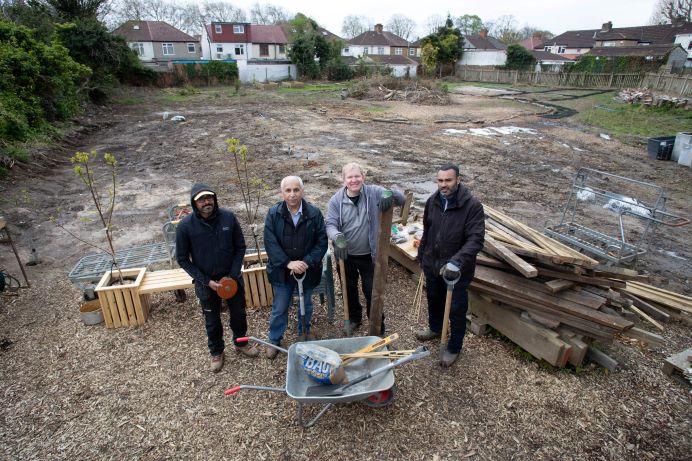 four volunteers with hand tools in the open space that has been cleared of waste