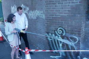 Cllr Mason and Cllr Costigan removing graffiti on wall
