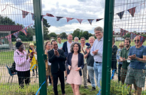 Councillor Costigan cutting a ribbon at a new allotment opening surrounded by partners and residents