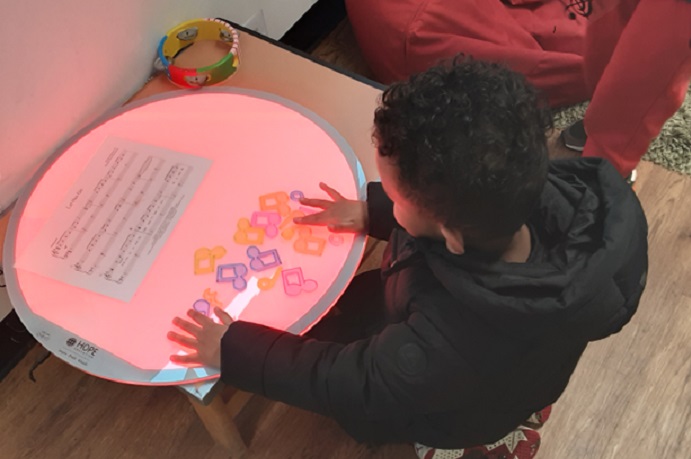 Child sitting at musical light table