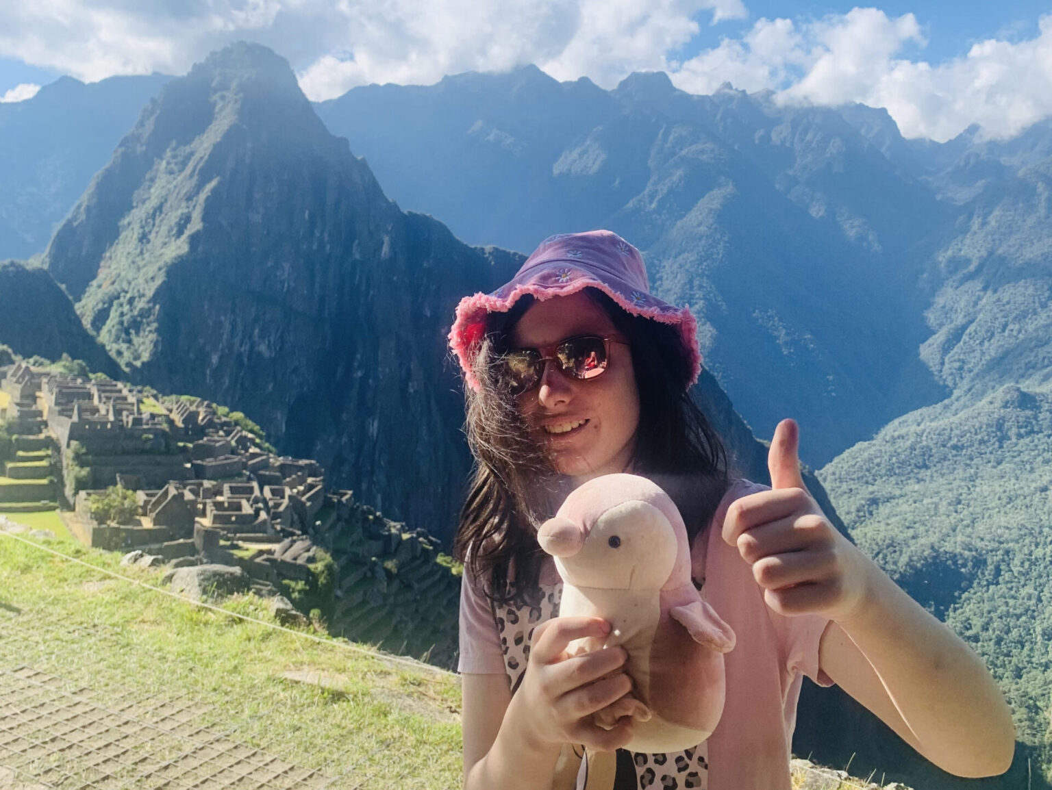 Girl standing on the side of a mountain, making a thumbs up sign